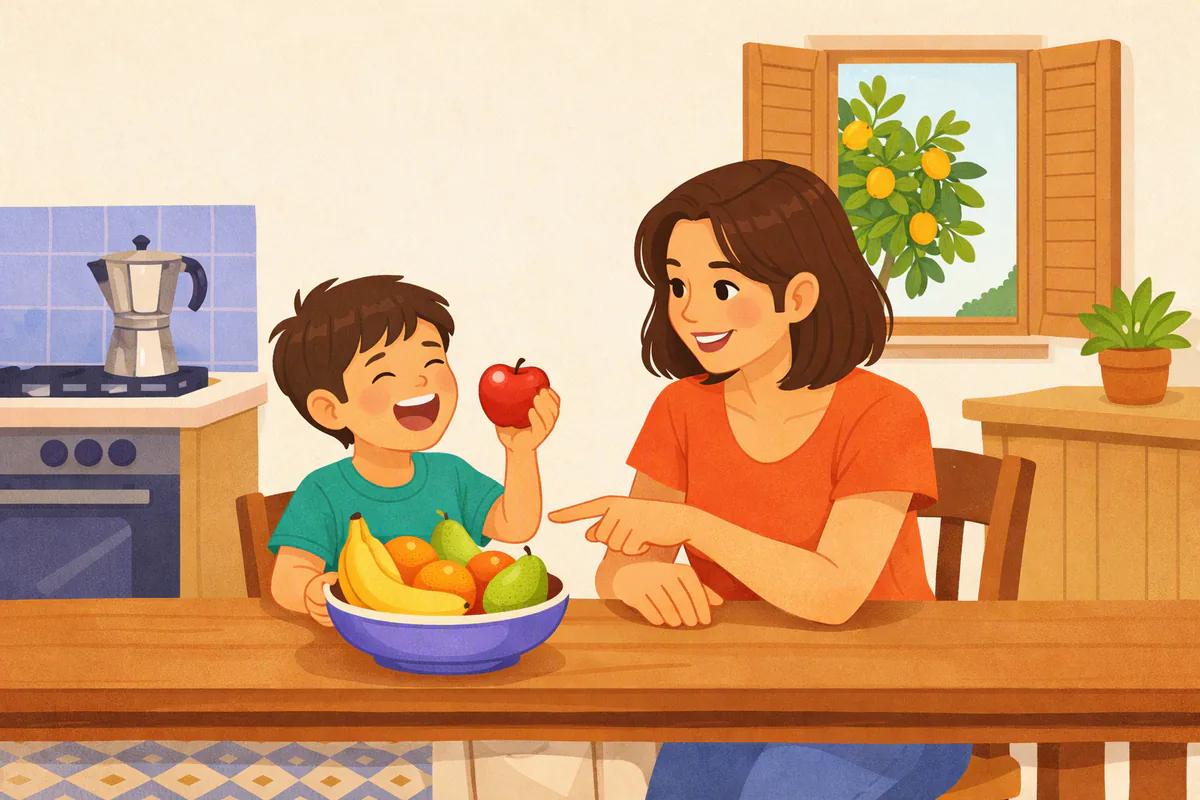 Una mamma e un bambino in cucina giocano a nominare la frutta sul tavolo, il bambino tiene in mano una mela rossa e ride